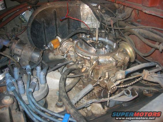 Engine bay showing a carburetor, distributor, spark plug wires, and fuel filter