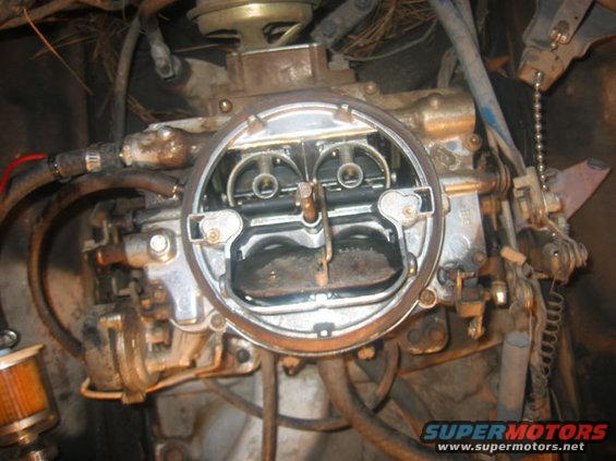 Close-up of a vehicle's carburetor with visible linkages and hoses