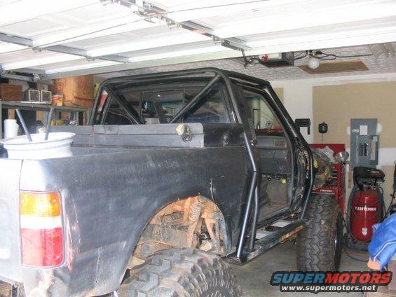 1986 Ford F-150 pickup truck with roll cage and large off-road tires, parked in a garage