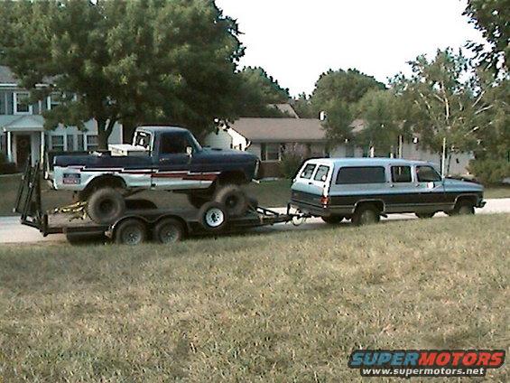 Side view of a 1977 Ford F-150 on a trailer, towed by an SUV