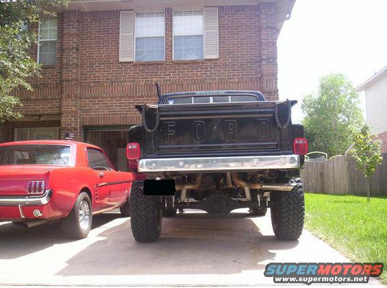 Rear view of a lifted black Ford pickup truck parked next to a red Ford Mustang