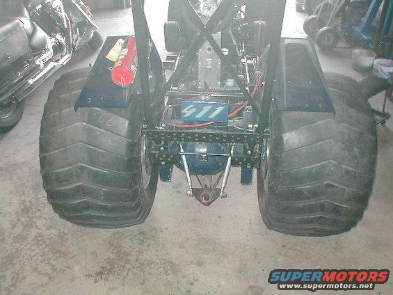 Monster truck rear axle with large tires, blue box labeled 411, and fire extinguisher