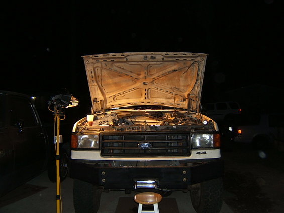 White Ford F-Series truck, front view, hood open, showing engine and grille with Ford logo. "4x4" badge visible