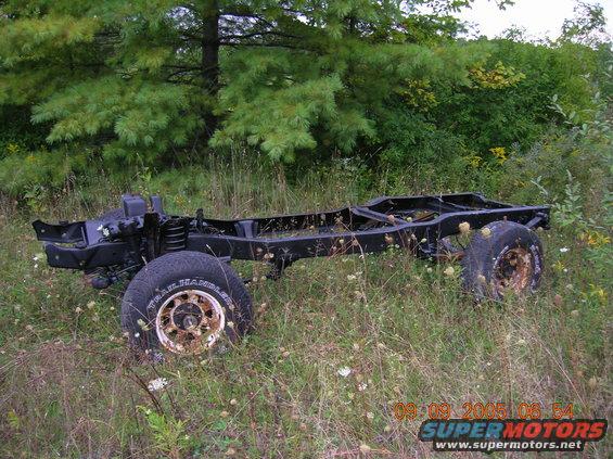 Vehicle chassis with wheels, overgrown with grass and weeds