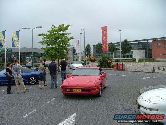 Red 1994 Ford Probe parked next to a blue Ford Probe, with several people standing around them