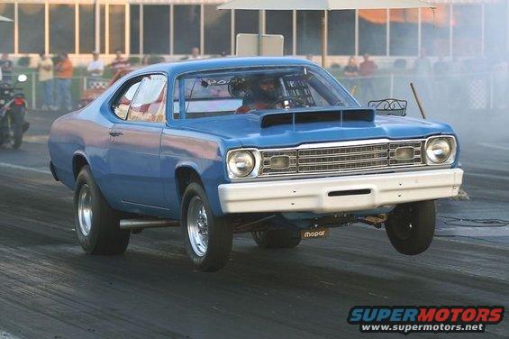 Blue drag car doing a wheelie on a track. Driver is wearing a helmet