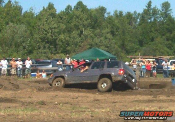 Gray SUV stuck in mud, rear wheel lifted