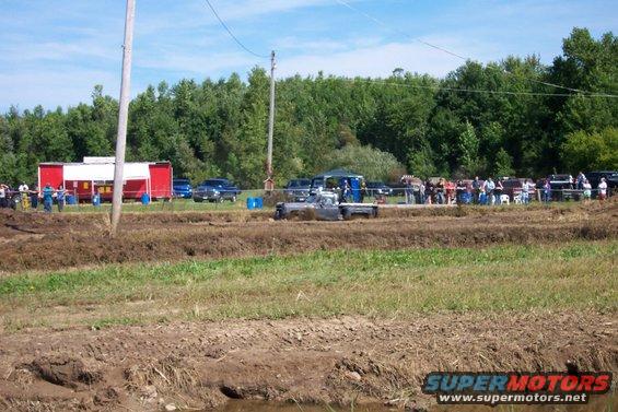 Mud bog event with a truck stuck in the mire and spectators watching