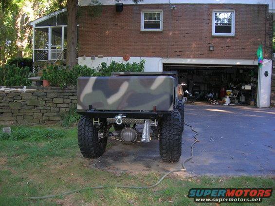 Rear view of a modified off-road vehicle with a camouflage bed, large tires, and a visible differential