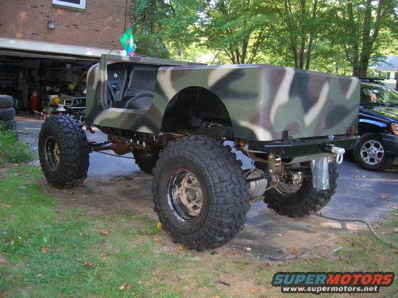 Camouflaged custom off-road vehicle rear view with large tires and winch