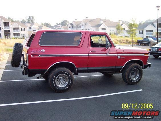 Red 1979 Ford Bronco parked in a lot, spare tire mounted on the back