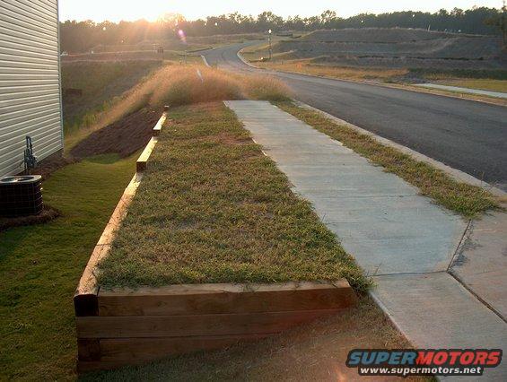 Suburban street with sidewalk and retaining wall at sunset