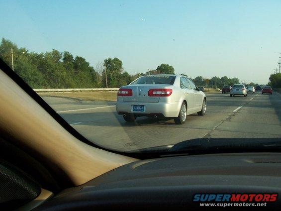 Silver sedan with a blue license plate driving on a highway