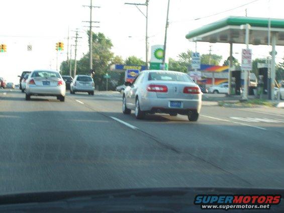 Silver sedan driving on highway, gas station in background. Looks like a 2005 model