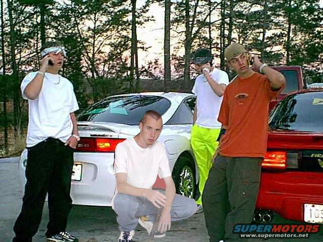 Four guys on phones with two cars, one white and one red