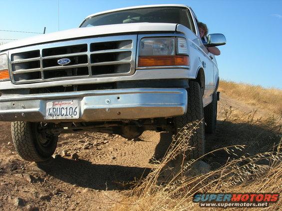 White Ford truck front view, chrome grille, California license plate 4RUC106, driving on dirt road