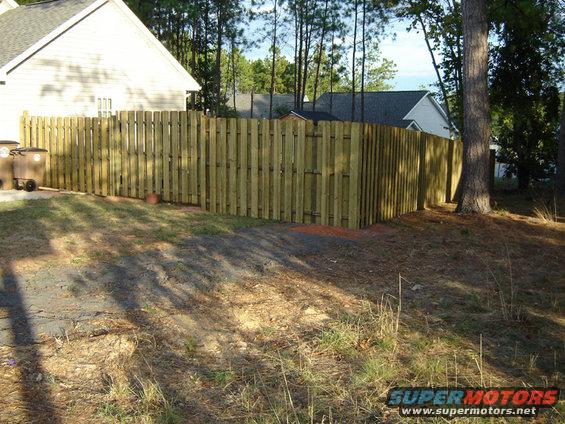 Wooden privacy fence surrounding a yard with houses and trees