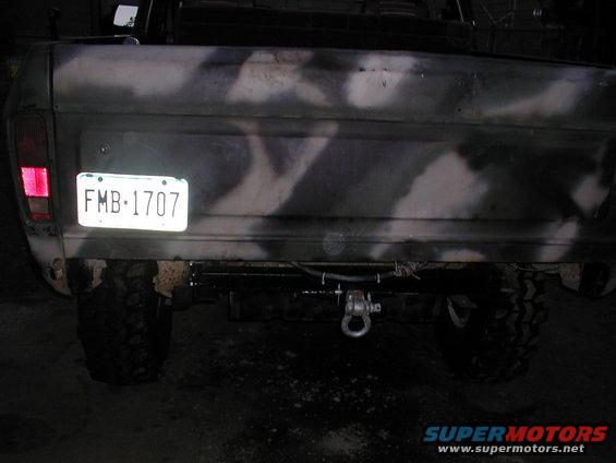 Camouflage-painted truck tailgate with license plate FMB-1707, tow hitch, and large tires