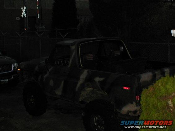 Camouflaged SUV parked next to another vehicle at night