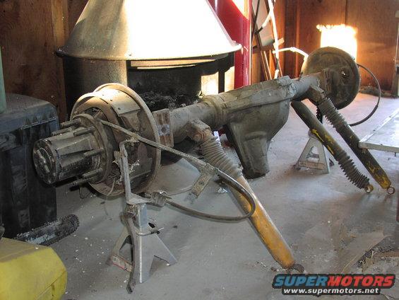 Rear axle assembly on jack stands with drum brakes and yellow shocks