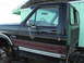 1983 Ford F-250 - The side of a dark-colored Ford F-350 truck cab is visible, with a "F350" badge and decorative stripes.