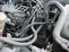 1983 Ford F-250 - Close-up view of a dusty engine bay, showing various hoses, wires, and engine components.