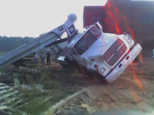 White truck tipped on its side with its front end visible, leaning against a building