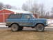 1979 Ford Bronco - A blue 1979 Ford Bronco is parked on a dirt road in front of a red barn.
