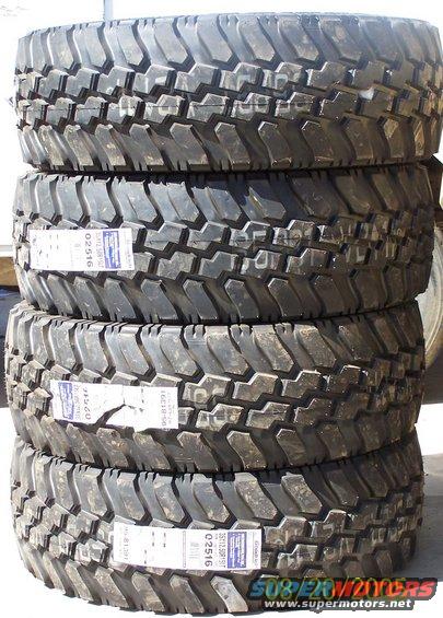 Stack of four off-road tires with white labels showing part numbers