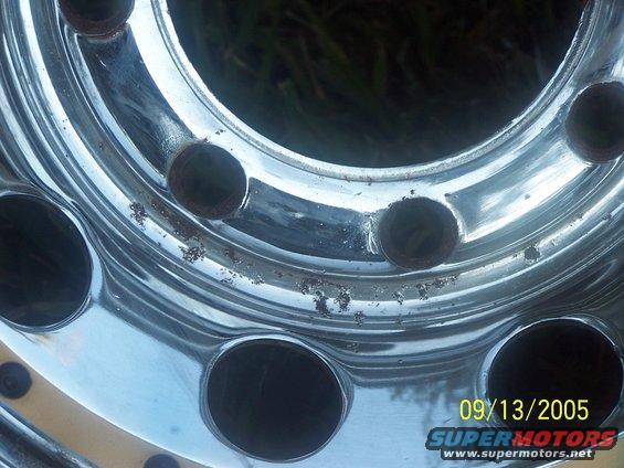 Chrome wheel with multiple lug nut holes and visible corrosion