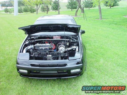 Black car with hood open showing engine bay, parked on grass