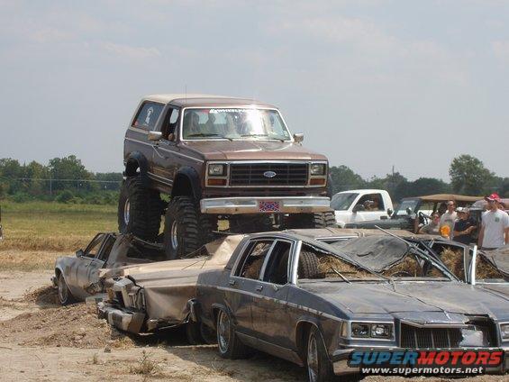 Brown lifted Ford Bronco on crushed cars