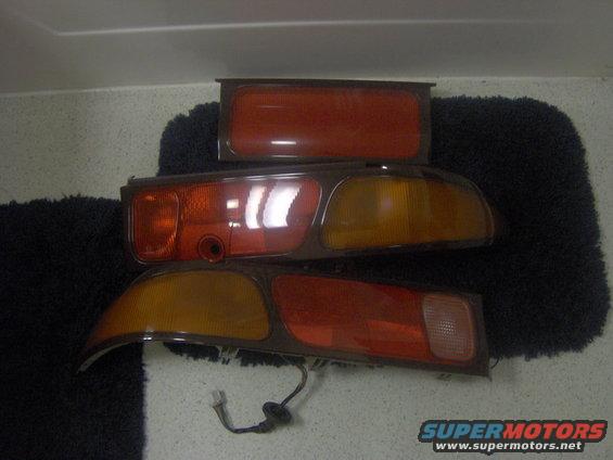 Three car taillights, two amber and red, one red, on a dark fuzzy surface