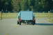 2005 Ford Deluxe - A vintage green coupe tows a white trailer from behind.