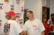 2005 Ford Deluxe - Two men shake hands in front of a "MotorsportsPark 131" banner. One man's shirt displays "HOT ROD DRAG WEEK 2005".