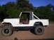 1982 Jeep CJ7 - This 1982 Jeep CJ7 features a white exterior, black roll bar, and brown interior, viewed from the side.