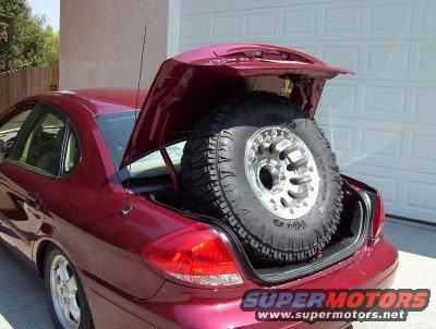 Red sedan with trunk open showing a large spare tire inside