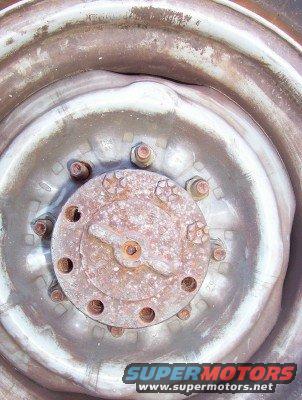Close-up of rusty wheel hub with lug nuts and part of a tire rim