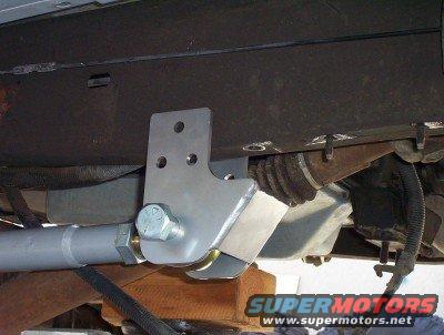 Close-up of a metal bracket bolted to a vehicle's frame, with a suspension component attached