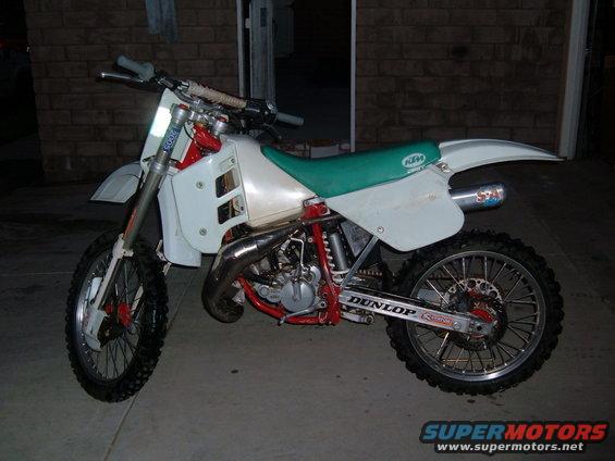 White dirt bike with green seat and red frame, side view