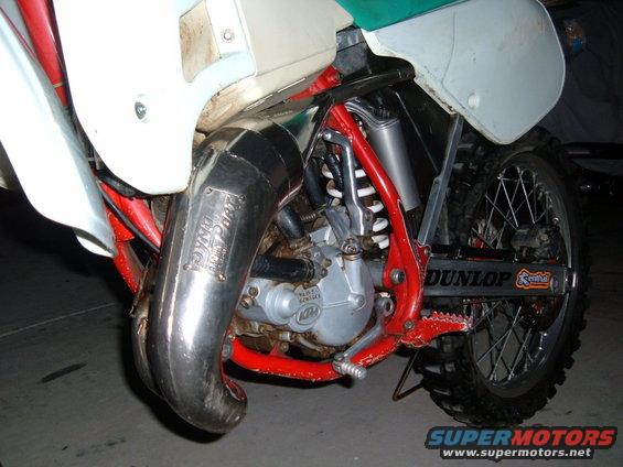 Close-up of a motorcycle's DynoJet exhaust pipe and engine components, with Dunlop tire visible