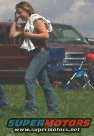Woman in jeans and t-shirt with towel over shoulder, standing in front of a maroon truck