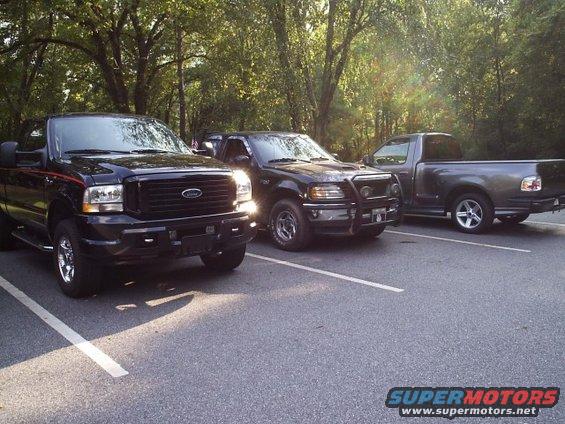 Three black Ford trucks parked in a lot, front view