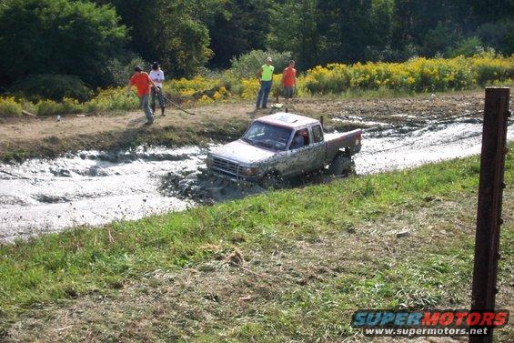 Silver pickup truck stuck in mud pit, 3/4 front view