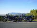 1981 Honda CB750 - Two motorcycles are parked on the side of a road, with a scenic mountain landscape behind them under a clear blue sky.