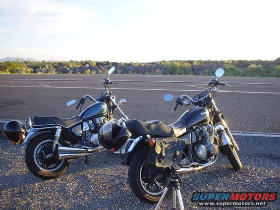 Two motorcycles parked on asphalt with a distant landscape