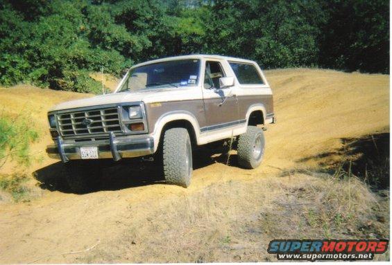 1982 Ford Bronco on a dirt hill, two-tone brown and white paint, lifted suspension