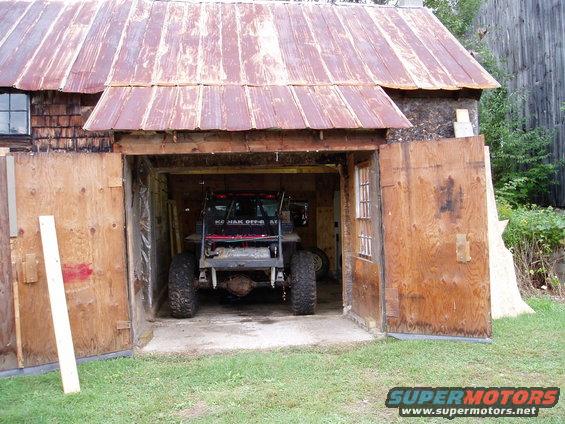 Off-road vehicle with large tires parked in a wooden garage