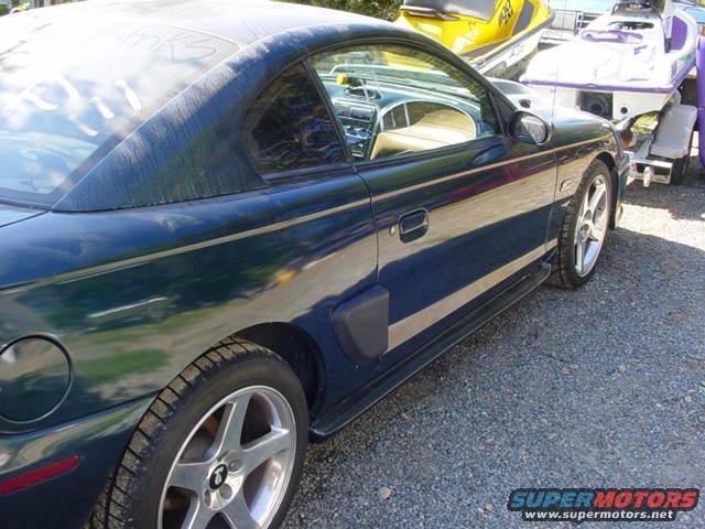 Dark green 1995 Ford Mustang coupe parked next to a trailer with two jet skis