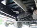 1995 Ford C-350 (Centurion Conversions) - Undercarriage view of a truck's drivetrain, with another vehicle visible in the background.